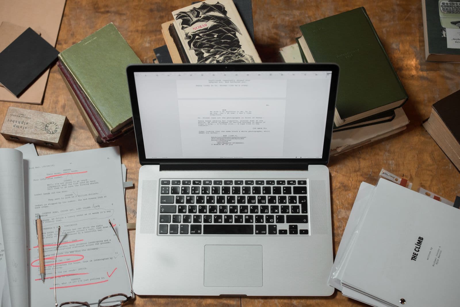 Laptop surrounded by academic books and research papers on a wooden desk for literature review analysis