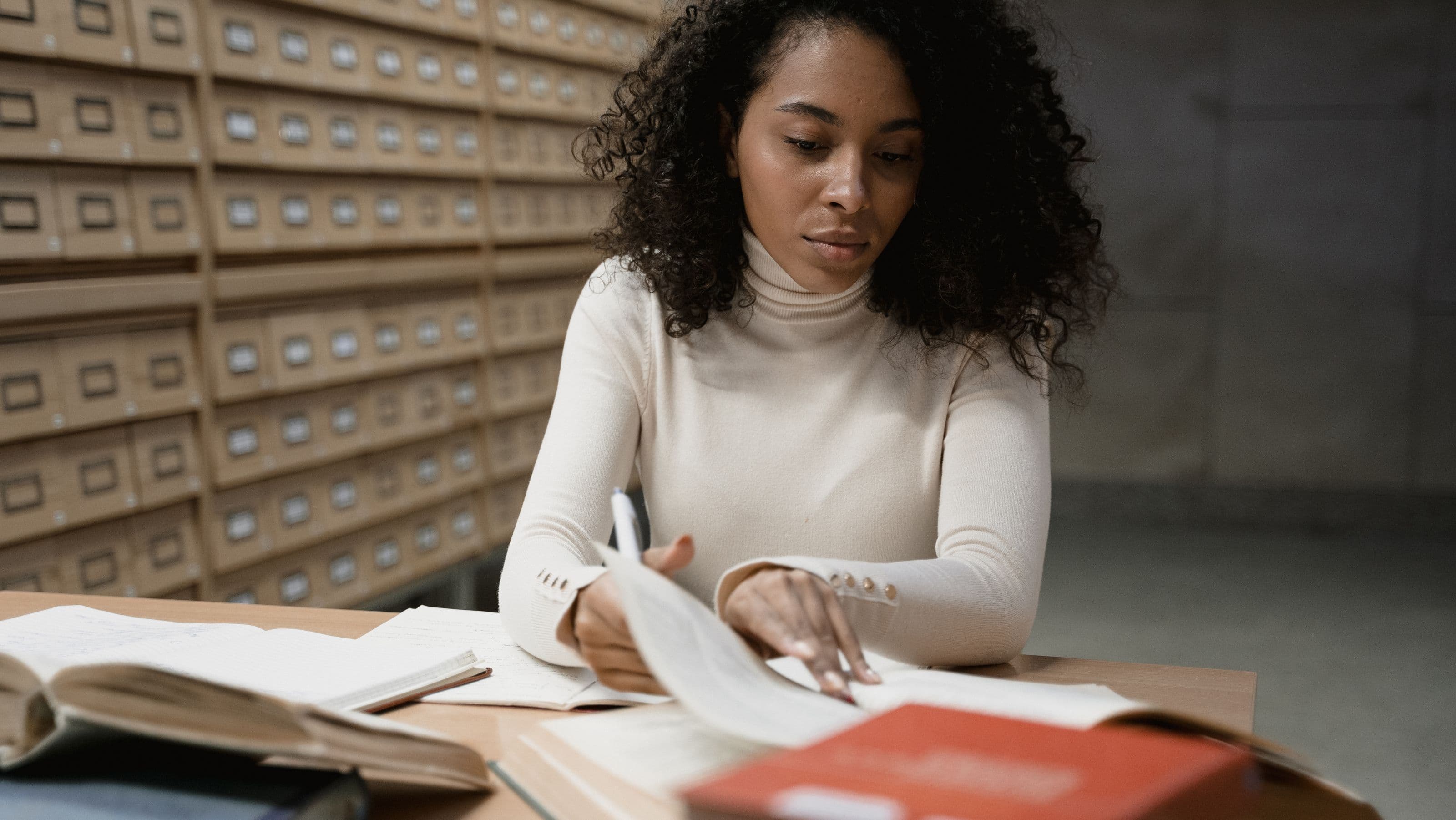 A researcher at a desk surrounded by open books, comparing sources while deciding on a methodology